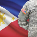 A soldier in a U.S. Army uniform with the Philippine flag in the background