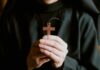 125 Years of Service Under Threat – Nuns Fight Back! A person holding a wooden cross pendant