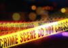 Yellow police tape marking a crime scene with blurred lights in the background