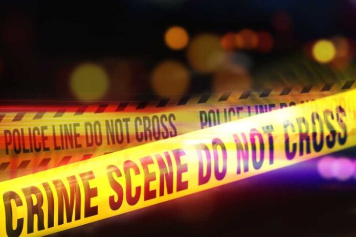 Yellow police tape marking a crime scene with blurred lights in the background