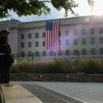 A Marine standing guard in front of the Pentagon with an American flag in the background