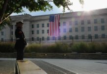 A Marine standing guard in front of the Pentagon with an American flag in the background