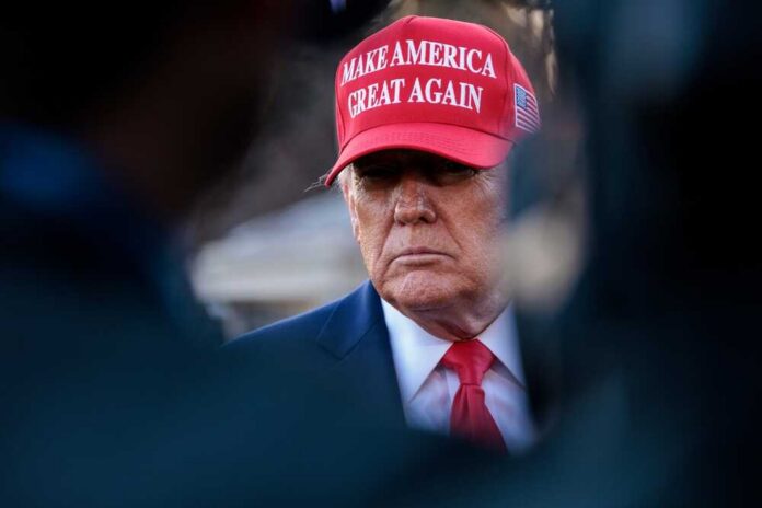 A political figure wearing a red hat with a serious expression