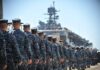 Navy personnel marching in formation towards a ship