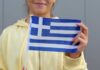 Young woman holding a small Greek flag