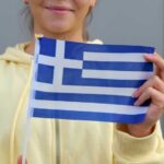 Young woman holding a small Greek flag