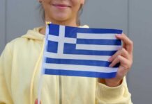 Young woman holding a small Greek flag