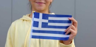 Young woman holding a small Greek flag