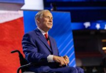 A man in a blue suit sitting in a wheelchair on a conference stage