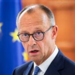 Troop Pullout Looms: What It Means for Europe A man in a suit with glasses, looking serious in front of an EU flag