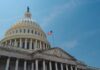The U.S. Capitol building with an American flag flying against a blue sky