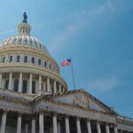 The U.S. Capitol building with an American flag flying against a blue sky