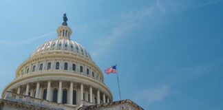 The U.S. Capitol building with an American flag flying against a blue sky