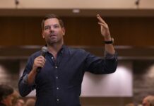 Democratic Leaders Turn on Swalwell – Urgent Ultimatum A speaker gesturing while holding a microphone during a presentation