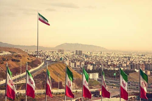 View of Iranian flags with a city and mountains in the background