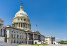 U.S. Capitol building with American flag, blue sky.