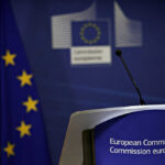 EU’s Wealth Tax Gamble: Repeating Past Failures? European Commission podium and flag background.