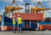 Two workers in safety gear at shipping port