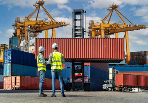 Two workers in safety gear at shipping port