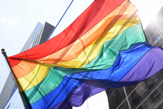 Rainbow,Flag,On,New,Building,Facing,An,Old,Building.,Pride A vibrant rainbow flag waving against a city backdrop