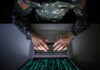 Big Tech Embeds AI—Military’s Secret Edge Revealed! A soldier in U.S. Army uniform typing on a laptop with green code displayed on the screen