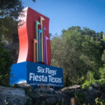 Colorful sign for Six Flags Fiesta Texas surrounded by greenery