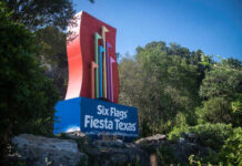 Colorful sign for Six Flags Fiesta Texas surrounded by greenery