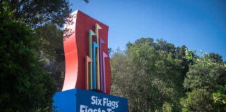Colorful sign for Six Flags Fiesta Texas surrounded by greenery