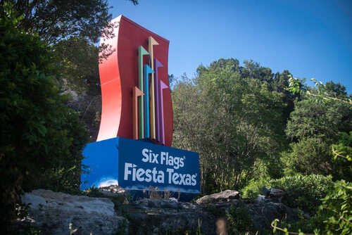 Colorful sign for Six Flags Fiesta Texas surrounded by greenery