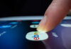 A finger tapping the eBay app icon on a smartphone screen