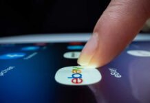 A finger tapping the eBay app icon on a smartphone screen