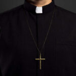 Tourist Trap: Rome’s Faux Clerical Calendar! Clerical shirt with a cross necklace against a dark background