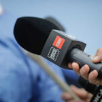 A hand holding a microphone with a CNN logo, ready for an interview