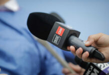 Paramount’s Shady Deal: CNN Anchors at Risk A hand holding a microphone with a CNN logo, ready for an interview