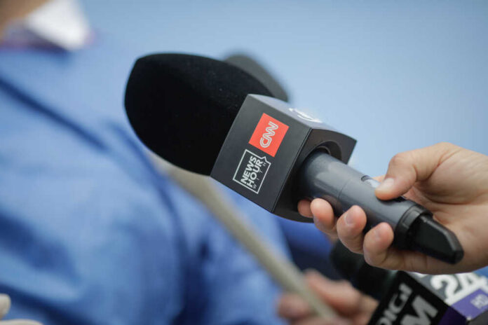 A hand holding a microphone with a CNN logo, ready for an interview