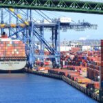 A cargo ship loaded with colorful containers docked at a busy shipping port