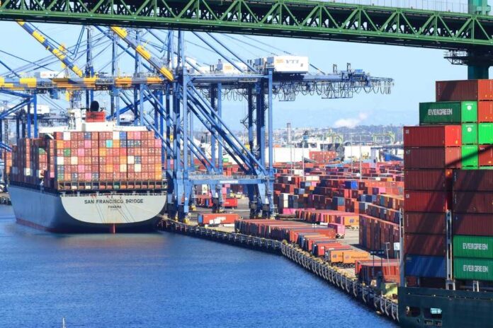 shutterstock_2062610534.jpg A cargo ship loaded with colorful containers docked at a busy shipping port