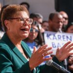 A woman speaking passionately at a political rally with supporters in the background