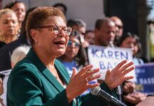 A woman speaking passionately at a political rally with supporters in the background