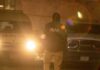 A law enforcement officer standing in front of police vehicles at night