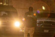 A law enforcement officer standing in front of police vehicles at night