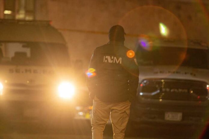 shutterstock_2324820705.jpg A law enforcement officer standing in front of police vehicles at night