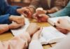 Watchdog on a Leash: Anti-Hate Group Loses Funding Over Christian Bias Scandal Group of hands holding each other over an open Bible