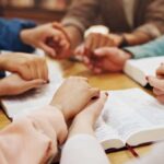Watchdog on a Leash: Anti-Hate Group Loses Funding Over Christian Bias Scandal Group of hands holding each other over an open Bible