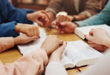 Watchdog on a Leash: Anti-Hate Group Loses Funding Over Christian Bias Scandal Group of hands holding each other over an open Bible