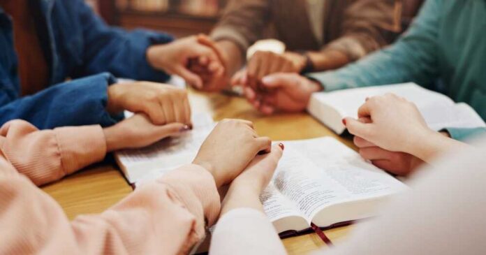 Bible,Study,,Holding,Hands,And,Group,With,Faith,,Praying,And Group of hands holding each other over an open Bible