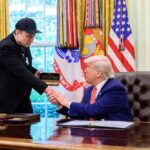 Two men shaking hands in the Oval Office during a meeting
