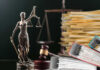 Lady Justice statue beside gavel and stacks of legal files