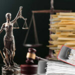 Lady Justice statue beside gavel and stacks of legal files