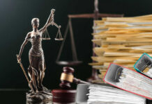 Lady Justice statue beside gavel and stacks of legal files